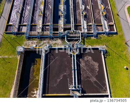Water treatment facility located in an urban area with multiple tanks and pipes seen from above during daytime hours Water treatment facility located in an urban area with multiple tanks and pipes seen from above during daytime hours 136734505