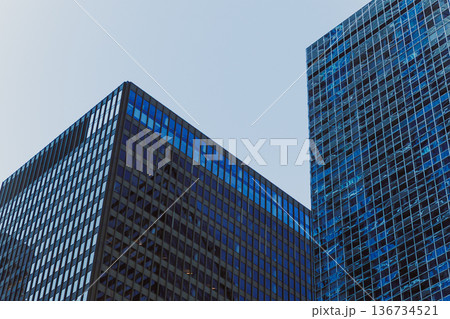 Modern buildings stand tall against the blue sky in an urban area showcasing glass and steel designs during daytime hours Modern buildings stand tall against the blue sky in an urban area showcasing glass and steel designs during daytime hours 136734521