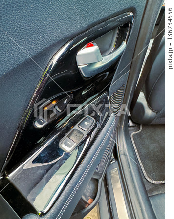 Close-up view of car door controls showing window switches and handle, taken in a vehicle parked outdoors during daylight Close-up view of car door controls showing window switches and handle, taken in a vehicle parked outdoors during daylight 136734556