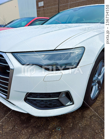 White car parked near buildings with droplets of water on its surface during daytime hours in a parking lot setting White car parked near buildings with droplets of water on its surface during daytime hours in a parking lot setting 136734558