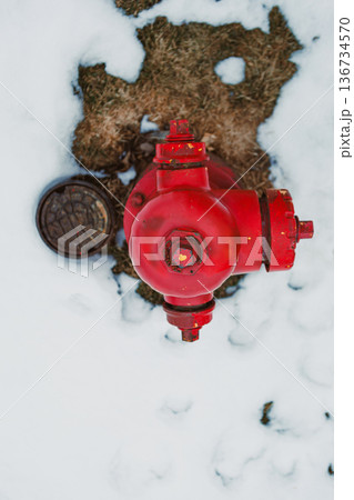Fire hydrant is visible in a snowy area next to a manhole cover during winter weather Fire hydrant is visible in a snowy area next to a manhole cover during winter weather 136734570