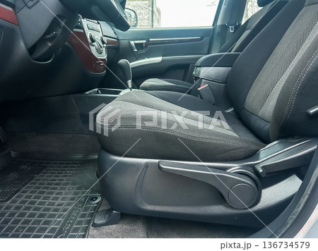 Inside view of a vehicle showing the front driver and passenger seats taken during daytime at a parking lot Inside view of a vehicle showing the front driver and passenger seats taken during daytime at a parking lot 136734579