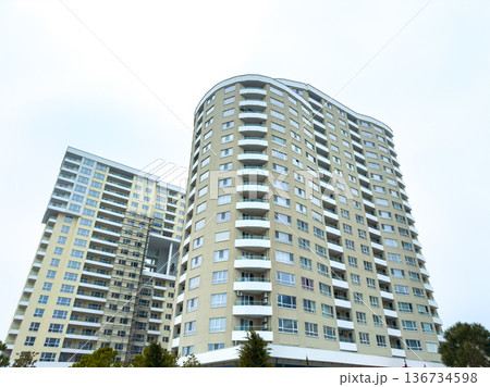 High-rise buildings stand in a city landscape under overcast skies in a suburban area, showcasing modern architecture and residential units 136734598