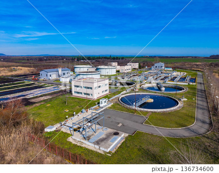 Water treatment plant operates in the rural area with large circular tanks and buildings during a clear day in early spring 136734600