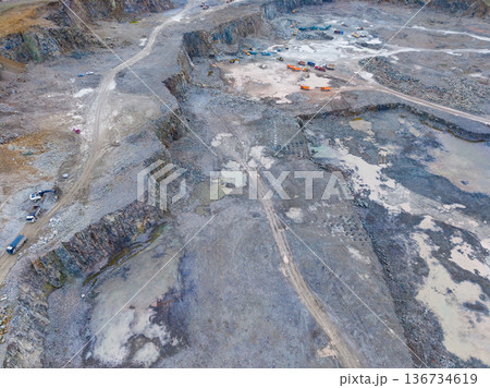 Large mining site shows heavy machinery and vehicles working on extraction and excavation activities in an open area during daytime 136734619