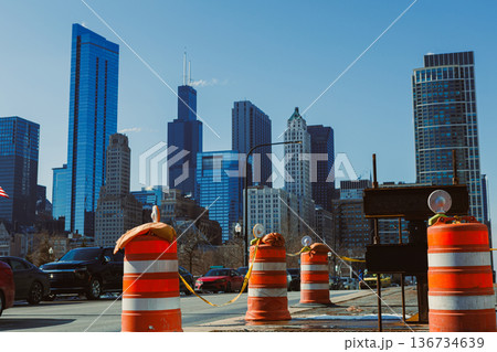 Construction barriers block a street in downtown Chicago with skyscrapers in the background on a clear day 136734639