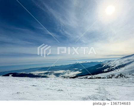 Snowy mountain landscape with a bright sun and distant hills during winter season Snowy mountain landscape with a bright sun and distant hills during winter season 136734683