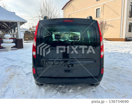 Black vehicle parked in snow-covered area near building during winter season with visible trees in the background Black vehicle parked in snow-covered area near building during winter season with visible trees in the background 136734690