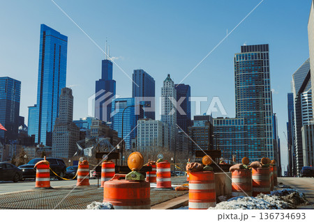 Construction work takes place on city street with traffic cones in foreground and tall buildings in the background during clear weather in downtown Chicago Construction work takes place on city street with traffic cones in foreground and tall buildings in the background during clear weather in downtown Chicago 136734693
