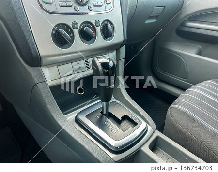 Detailed view of a car's gear shift and center console showing controls and layout during daylight in a parked vehicle Detailed view of a car's gear shift and center console showing controls and layout during daylight in a parked vehicle 136734703