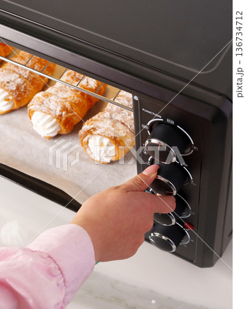Baking dessert pastries in an oven with cream filling and powdered sugar at home Baking dessert pastries in an oven with cream filling and powdered sugar at home 136734712