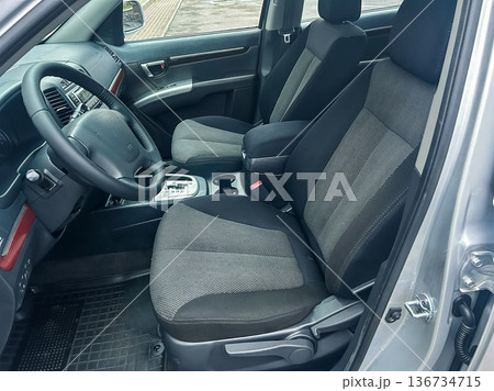 Vehicle interior shows front seats and dashboard with gear shift in a parked car at a location with no visible surroundings during daylight 136734715