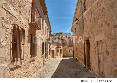 Narrow medieval street with traditional stone houses under the blue sky of Pedraza 136734781