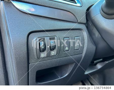 Switch panel located on the interior dashboard of a car showing multiple controls for lights and hazards during daylight hours Switch panel located on the interior dashboard of a car showing multiple controls for lights and hazards during daylight hours 136734864