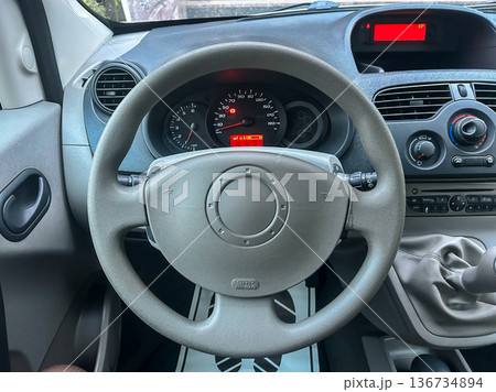 Detailed view of a car interior showing the steering wheel, dashboard, and controls during the day in a parked vehicle Detailed view of a car interior showing the steering wheel, dashboard, and controls during the day in a parked vehicle 136734894