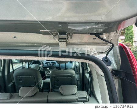 Car trunk showing hinges and interior view in a parking area during daylight hours 136734912