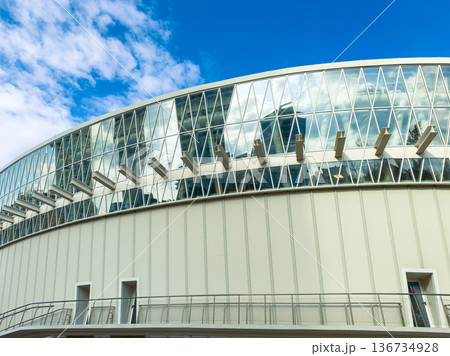 Modern building with large glass windows and outdoor walkway against blue sky in a city 136734928