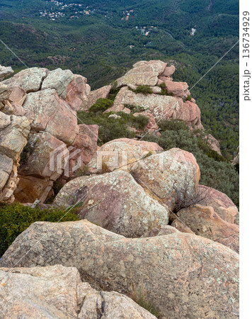 View from the top of the mountain showing rocky terrain and greenery below with a vast landscape in the distance during daylight hours View from the top of the mountain showing rocky terrain and greenery below with a vast landscape in the distance during daylight hours 136734929