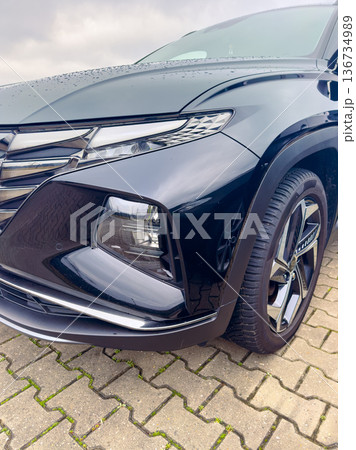 Black vehicle parked on a gray stone surface on a cloudy day with water droplets on the front end and a reflective surface Black vehicle parked on a gray stone surface on a cloudy day with water droplets on the front end and a reflective surface 136734989