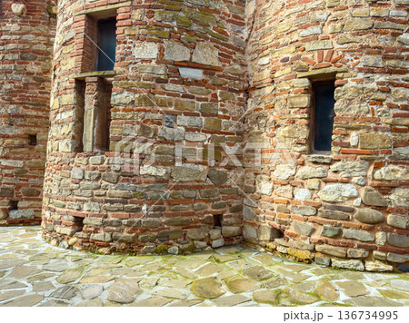 Old stone building with weathered walls near a cobblestone path in a historic location during daylight 136734995