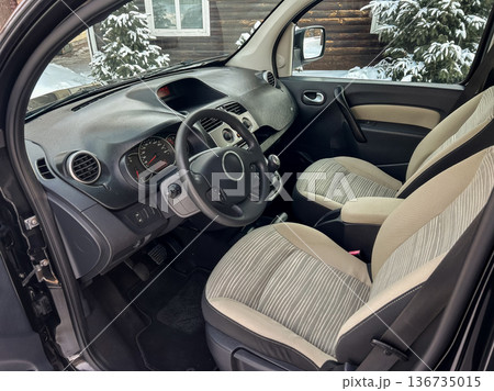 Interior of a car with light seats and steering wheel in winter setting near a house 136735015