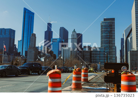 Construction work takes place on a city street in Chicago with tall buildings in the background under clear blue sky 136735023