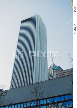 Tall building stands against blue sky in a city with modern architecture and clear weather during daytime Tall building stands against blue sky in a city with modern architecture and clear weather during daytime 136735050