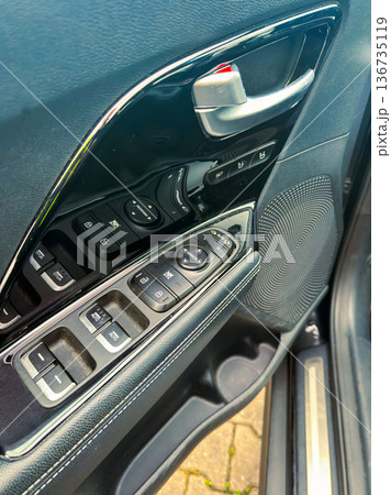 Inside a car showing the door control panel and speaker location at a parking spot during daytime Inside a car showing the door control panel and speaker location at a parking spot during daytime 136735119