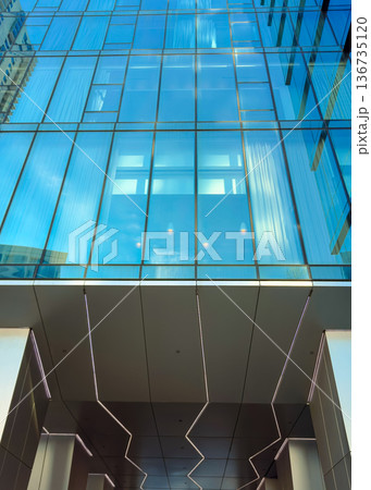 Clear glass building reflects light and sky in urban setting at midday with modern design and architecture features Clear glass building reflects light and sky in urban setting at midday with modern design and architecture features 136735120