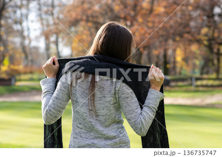 Woman with scarf in autumn park, back view 136735747