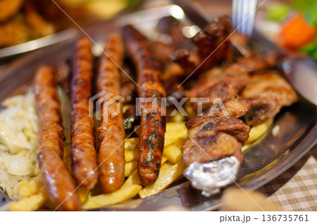 Mixed grilled meats and sausages with fries on tray 136735761