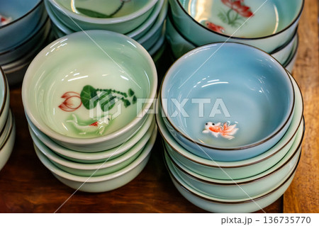 Stacked pastel ceramic tea cups with floral and koi designs Stacked pastel ceramic tea cups with floral and koi designs 136735770
