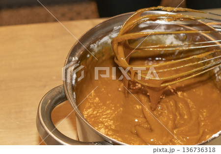 A person whisks the sauce in a pot 136736318