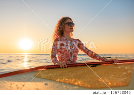 Young woman walking on stand up paddle sup boards by the sea during summer vacation Young woman walking on stand up paddle sup boards by the sea during summer vacation 136738049