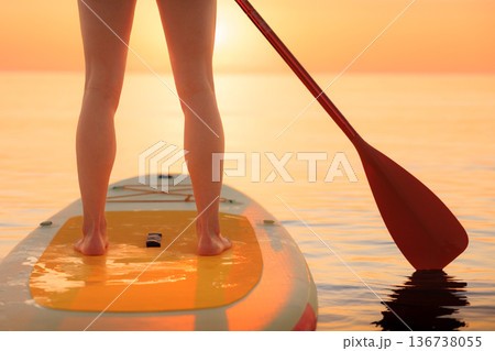 Young woman walking on stand up paddle sup boards by the sea during summer vacation Young woman walking on stand up paddle sup boards by the sea during summer vacation 136738055