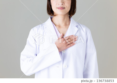 胸に手を当てる白衣姿のミドル女性医師 胸に手を当てる白衣姿のミドル女性医師 136738853