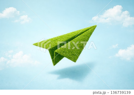 Eco friendly grass paper airplane flying in blue sky sustainability concept Eco friendly grass paper airplane flying in blue sky sustainability concept 136739139