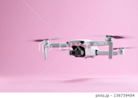 Modern white quadcopter drone flying against soft pastel pink studio background with copy space Modern white quadcopter drone flying against soft pastel pink studio background with copy space 136739484