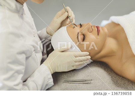 Esthetician performing blackhead extraction with tool during professional facial care Esthetician performing blackhead extraction with tool during professional facial care 136739858
