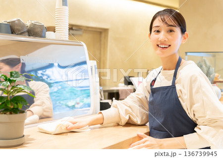 カフェのカウンターを拭き掃除している若い女性店員 カフェのカウンターを拭き掃除している若い女性店員 136739945