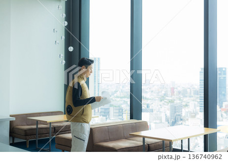 資料を見ながら現場を確認する空調服の職人の男性 136740962