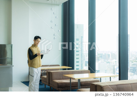 資料を見ながら現場を確認する空調服の職人の男性 136740964