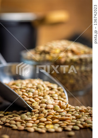 Uncooked green lentil on scoop on wooden table. Uncooked green lentil on scoop on wooden table. 136742023