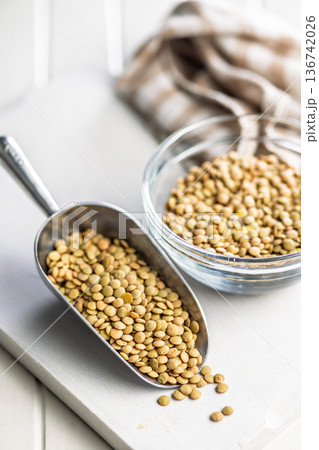 Uncooked green lentil in scoop on white table. 136742026