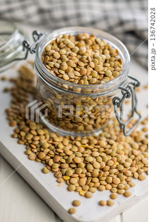 Uncooked green lentil in jar on white table. 136742028