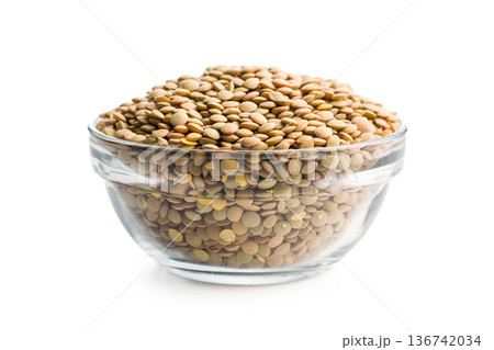 Uncooked green lentil in bowl isolated on white background. Uncooked green lentil in bowl isolated on white background. 136742034