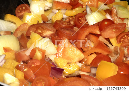 Close up of mixed fried vegetables chopped tomatoes, onions and peppers frying 136745209
