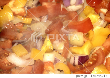 Close up of mixed fried vegetables chopped tomatoes, onions and peppers frying 136745217