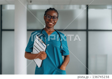 Documents in notepad. Female doctor is indoors in modern room Documents in notepad. Female doctor is indoors in modern room 136745238