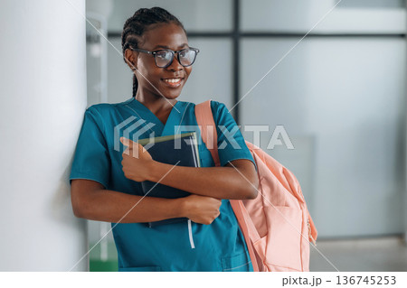 Book and notepads, learning material. Woman student with pink backpack is indoors Book and notepads, learning material. Woman student with pink backpack is indoors 136745253